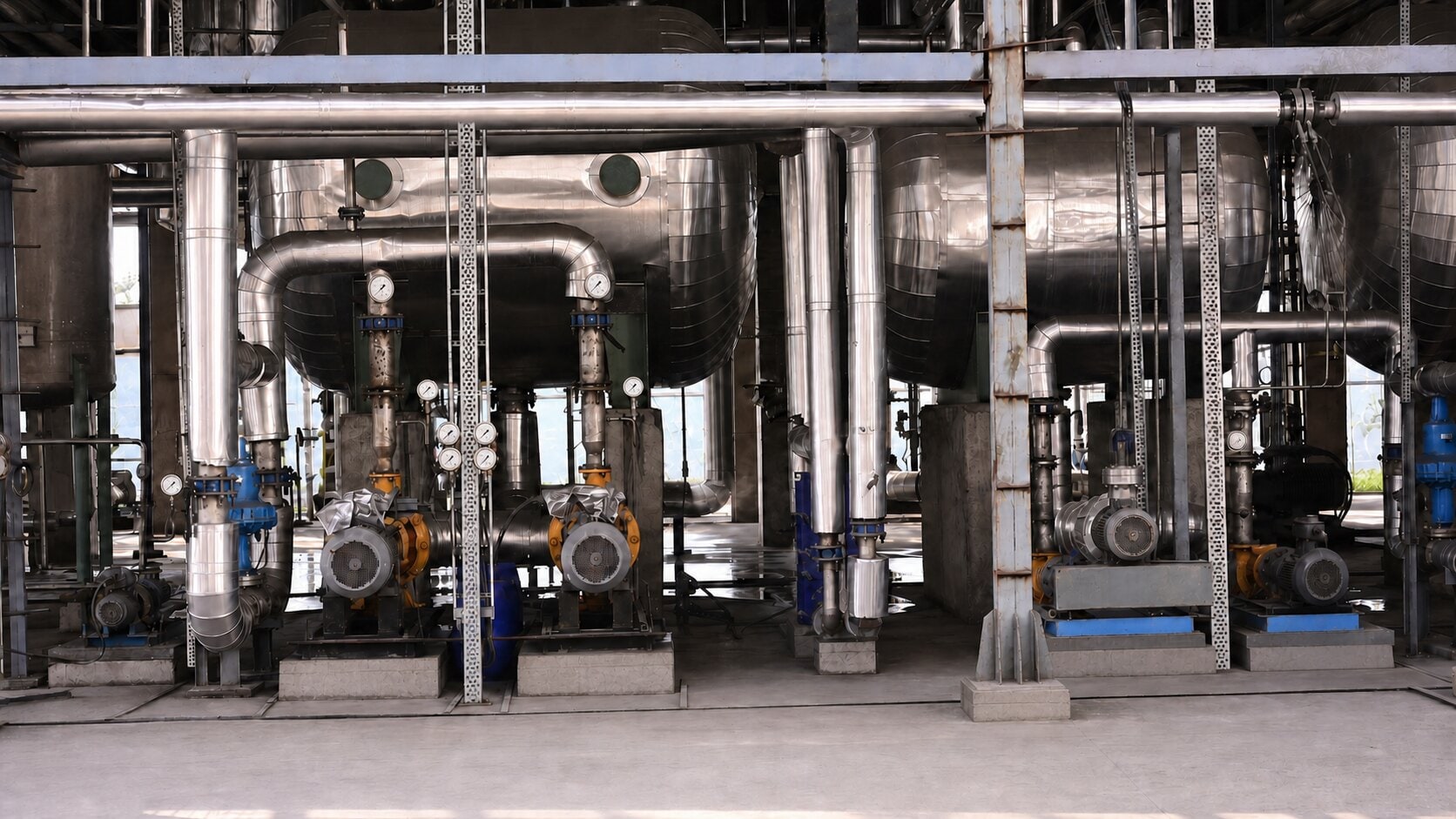 Inside the Inland Green Energy ethanol distillery — stainless distillation columns, insulated pipework and pump skids.