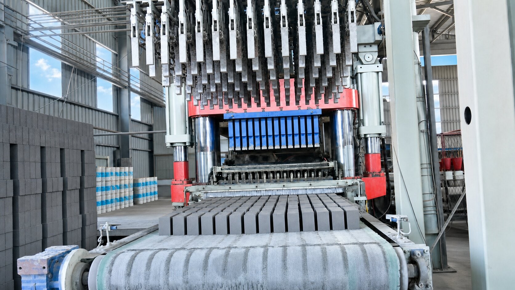 The fly-ash brick plant — a hydraulic press forming steam-cured bricks beside stacks of cured units.